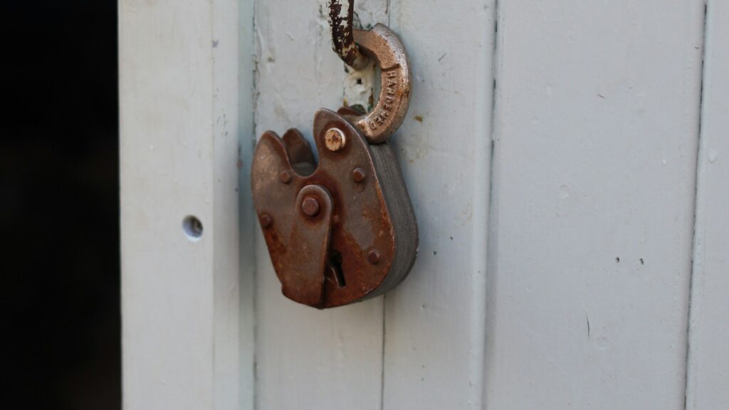 Candado oxidado en una puerta de madera, símbolo de la vulnerabilidad de una vivienda ante robos