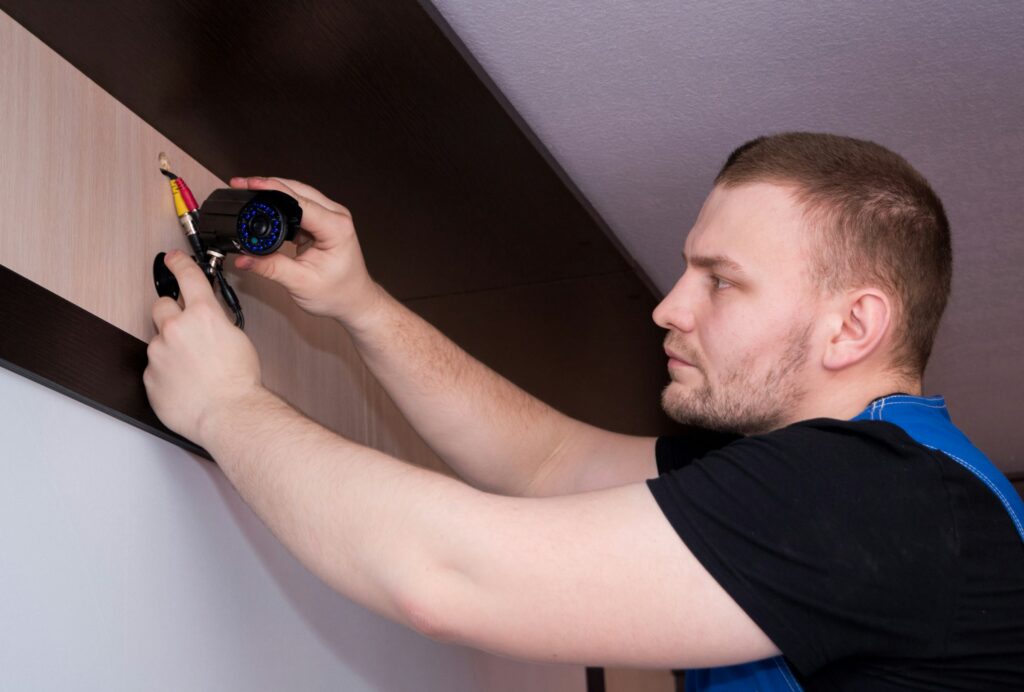 Técnico instalando una cámara de videovigilancia en la pared para un sistema de alarma profesional